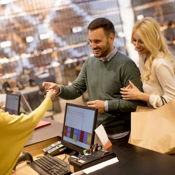 young-couple-paying-female-sales-assistant-with-credit-card-in-clothes-shop